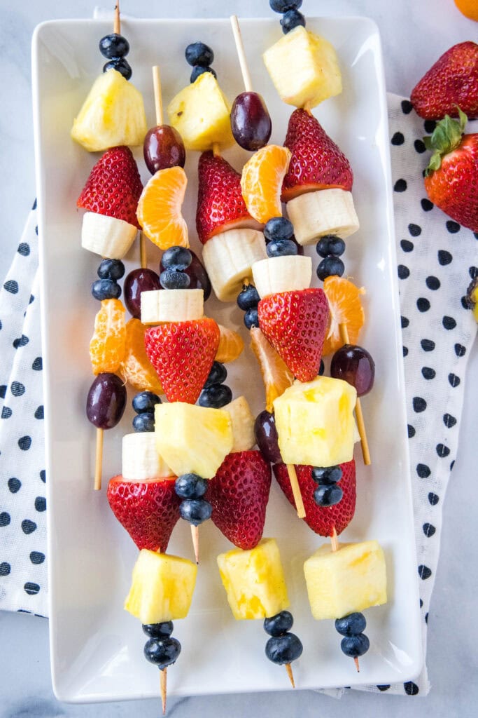 fruit skewers on a white platter