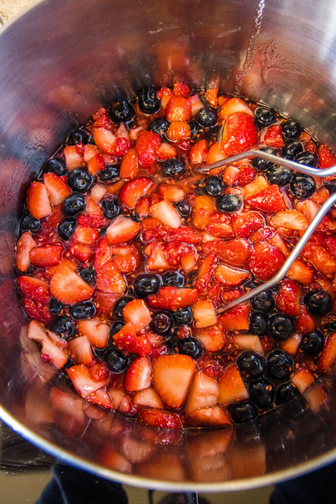 macerated berries in a stock pot with a potato masher mixed berry jam - dinners, dishes, and desserts - Mixed Berry Jam 3 683x1024 - Mixed Berry Jam &#8211; Dinners, Dishes, and Desserts