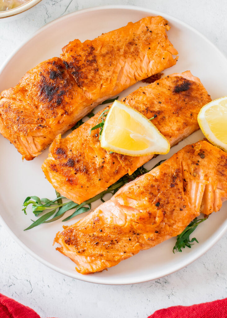 seared salmon on plate with lemon slices