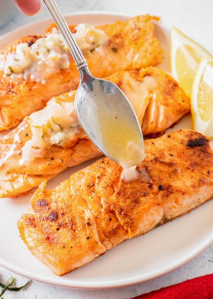 pan seared salmon with butter sauce being drizzled on