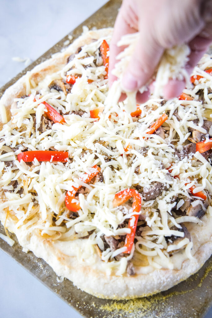 sprinkling cheese on pizza philly cheesesteak pizza - dinners, dishes, and desserts - Philly Cheesesteak Pizza 2 683x1024 - Philly Cheesesteak Pizza &#8211; Dinners, Dishes, and Desserts