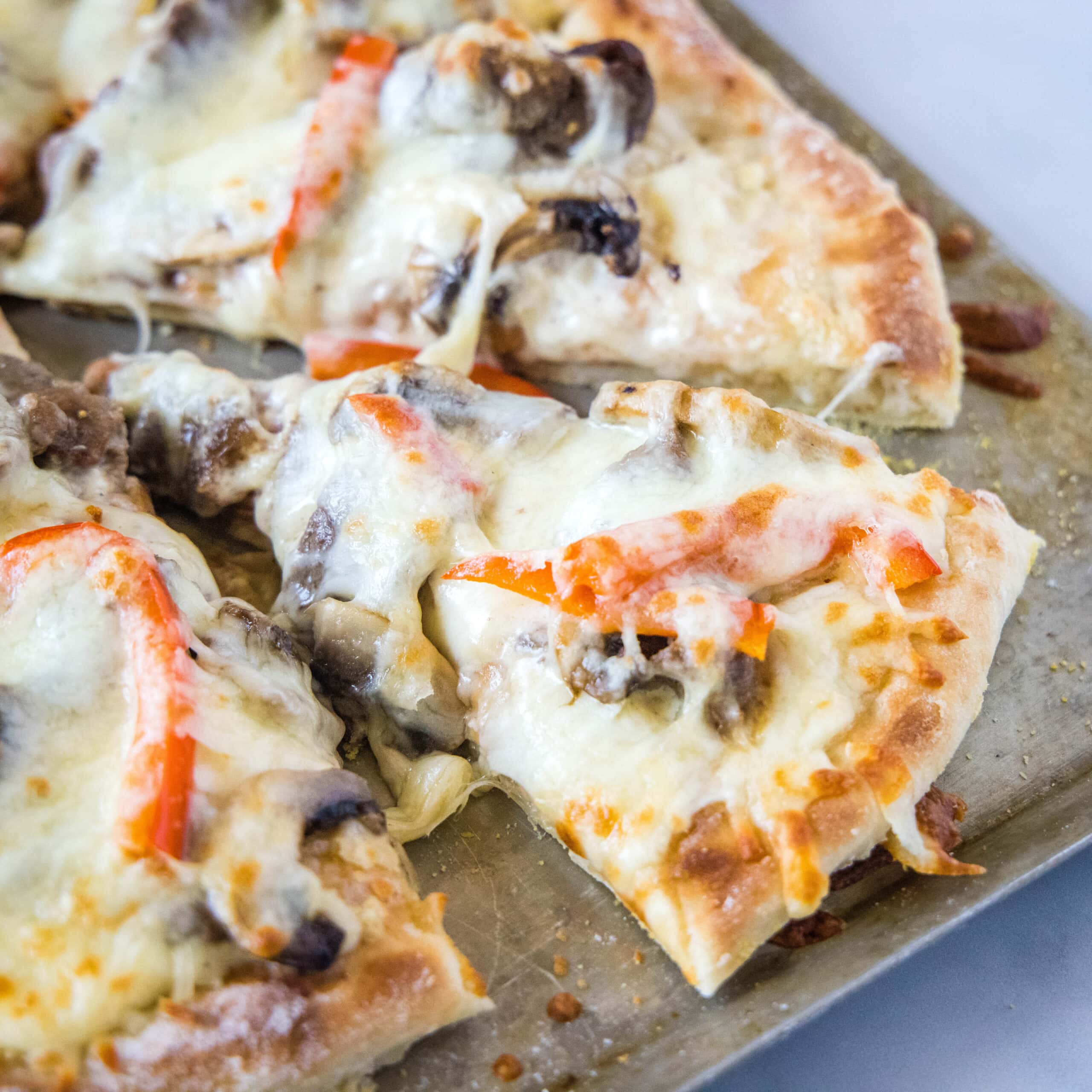 close up of slice of pizza on baking tray philly cheesesteak pizza - dinners, dishes, and desserts - Philly Cheesesteak Pizza square scaled - Philly Cheesesteak Pizza &#8211; Dinners, Dishes, and Desserts