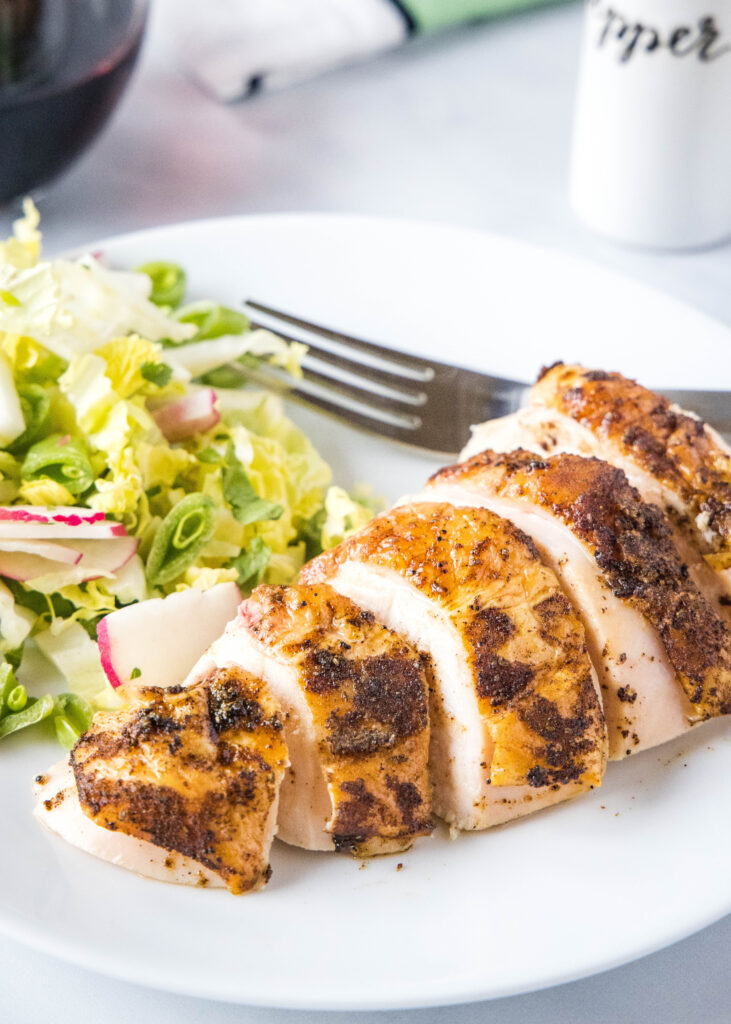 sliced chicken on a white plate with salad