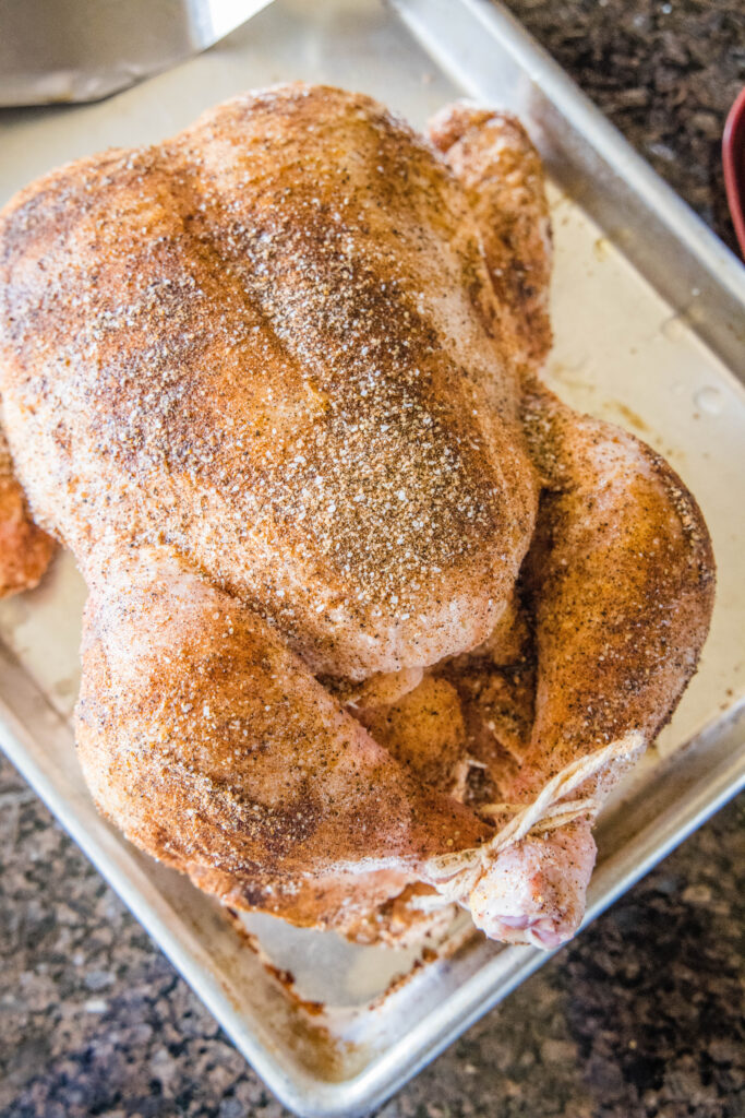whole chicken with a spice rub on a baking sheet