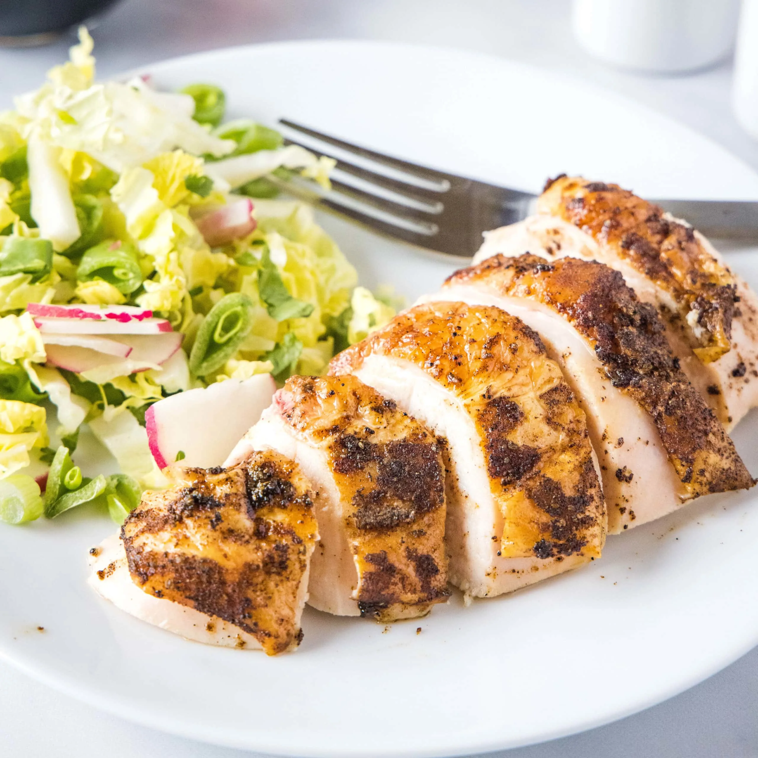 close up sliced chicken on a white plate with a fork