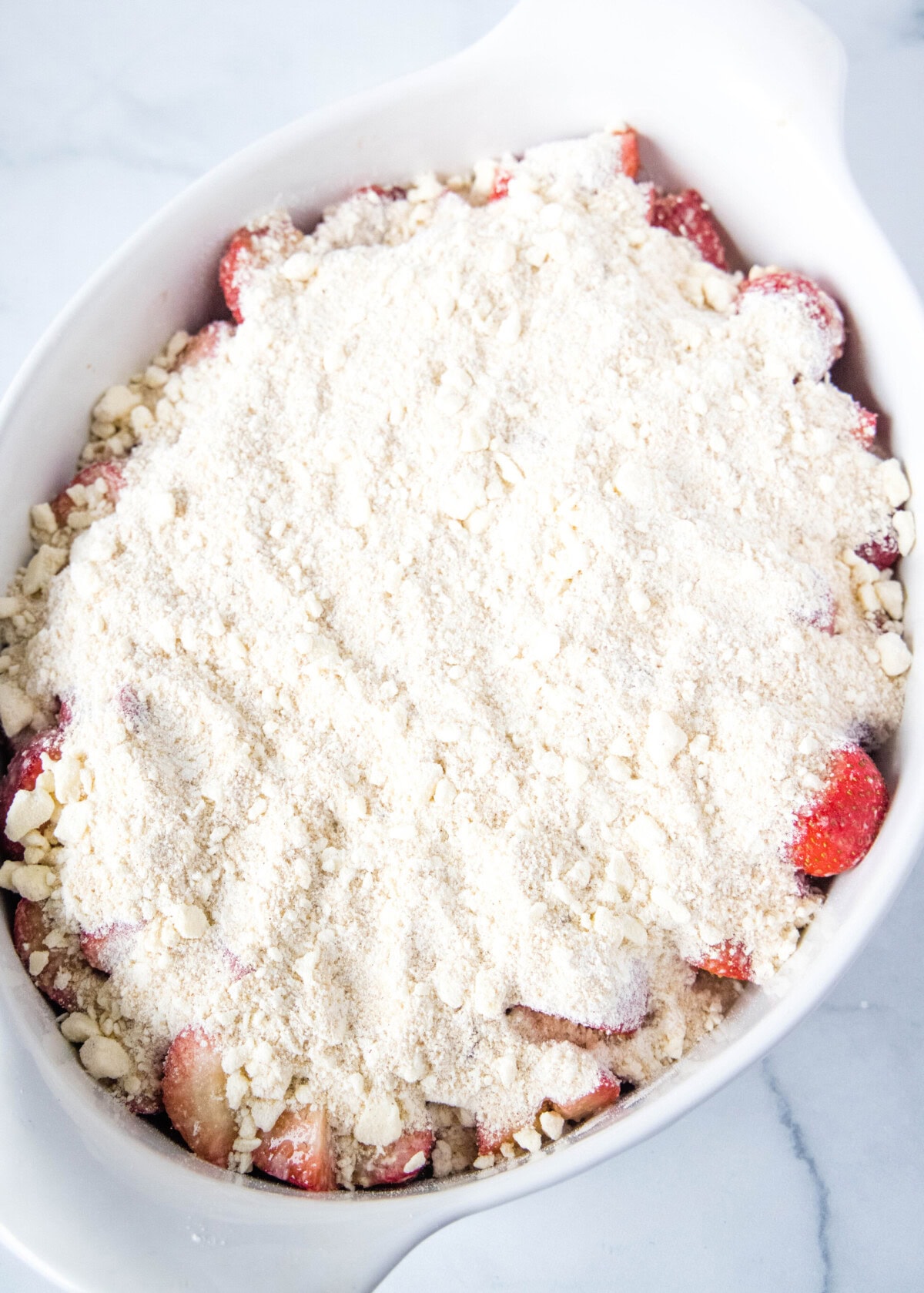 baking dish with strawberries and crumb topping ready for the oven
