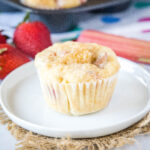 close up strawberry rhubarb muffin on white plate