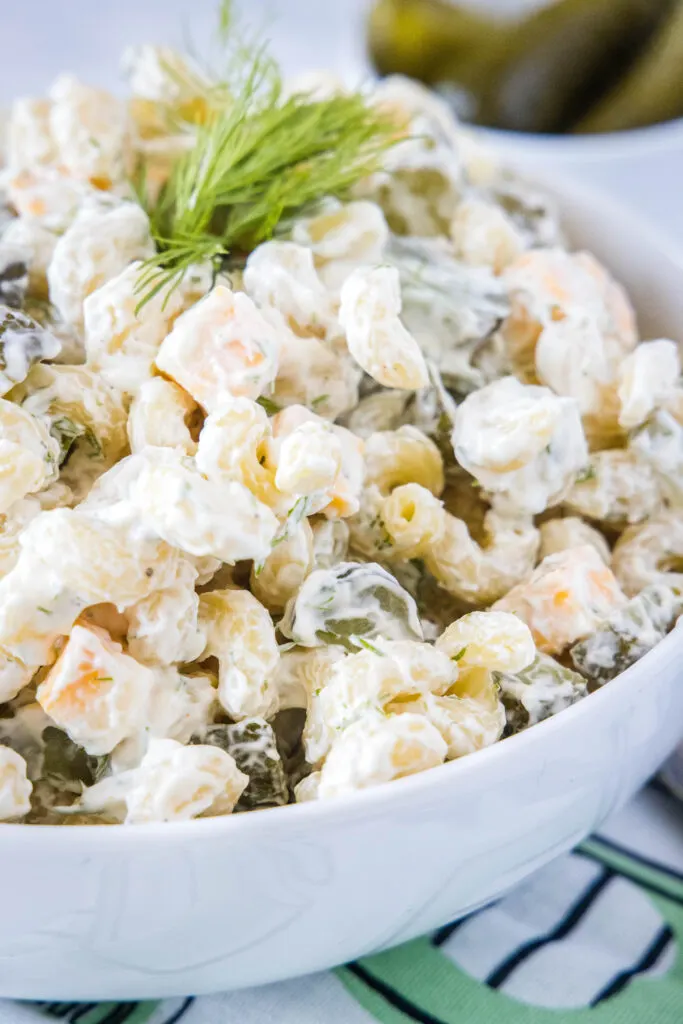 a bowl of pasta salad with pickles and cheese