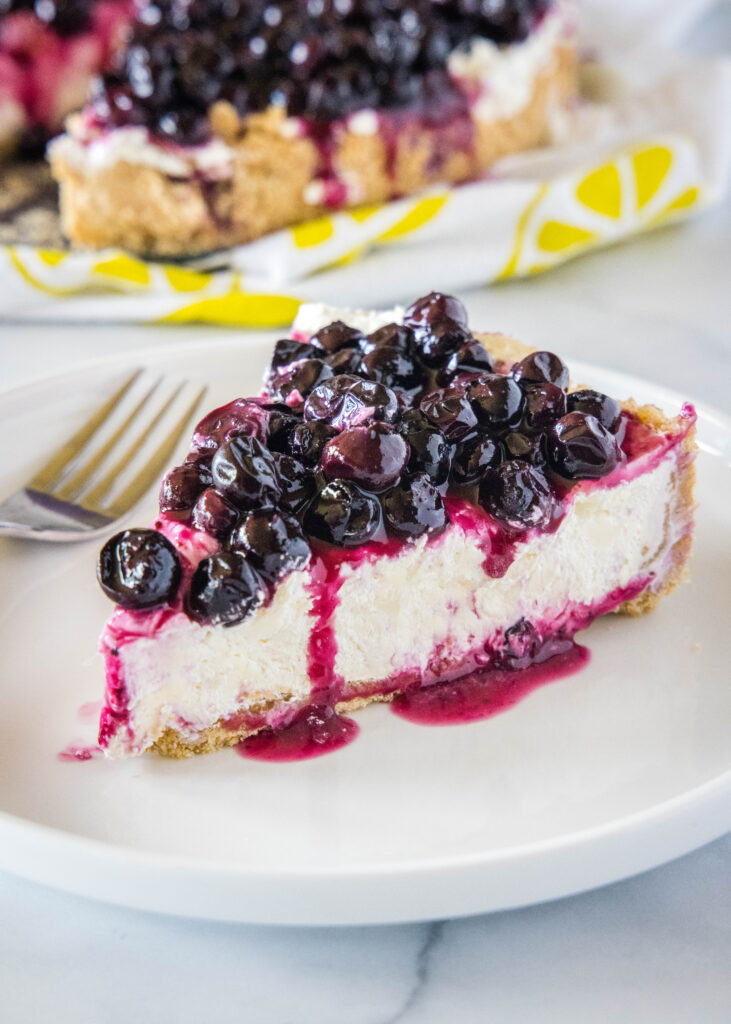 slice of no bake cheesecake topped with blueberries on a white plate