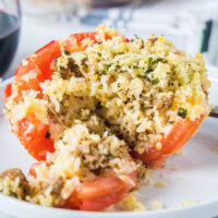 close up baked stuffed tomato cut open to see rice and sausage