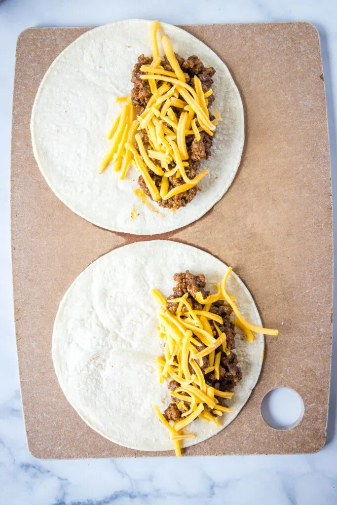 filling tortillas with taco meat and cheese