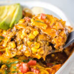 close up scooping beef enchilada casserole out of the pan