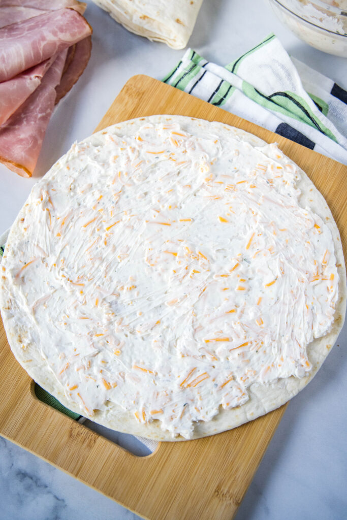spreading cream cheese mixture over a tortilla