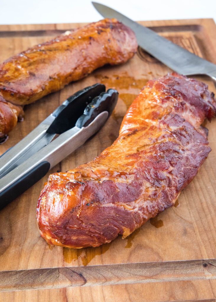 smoked pork tenderloin on a cutting board with a knife