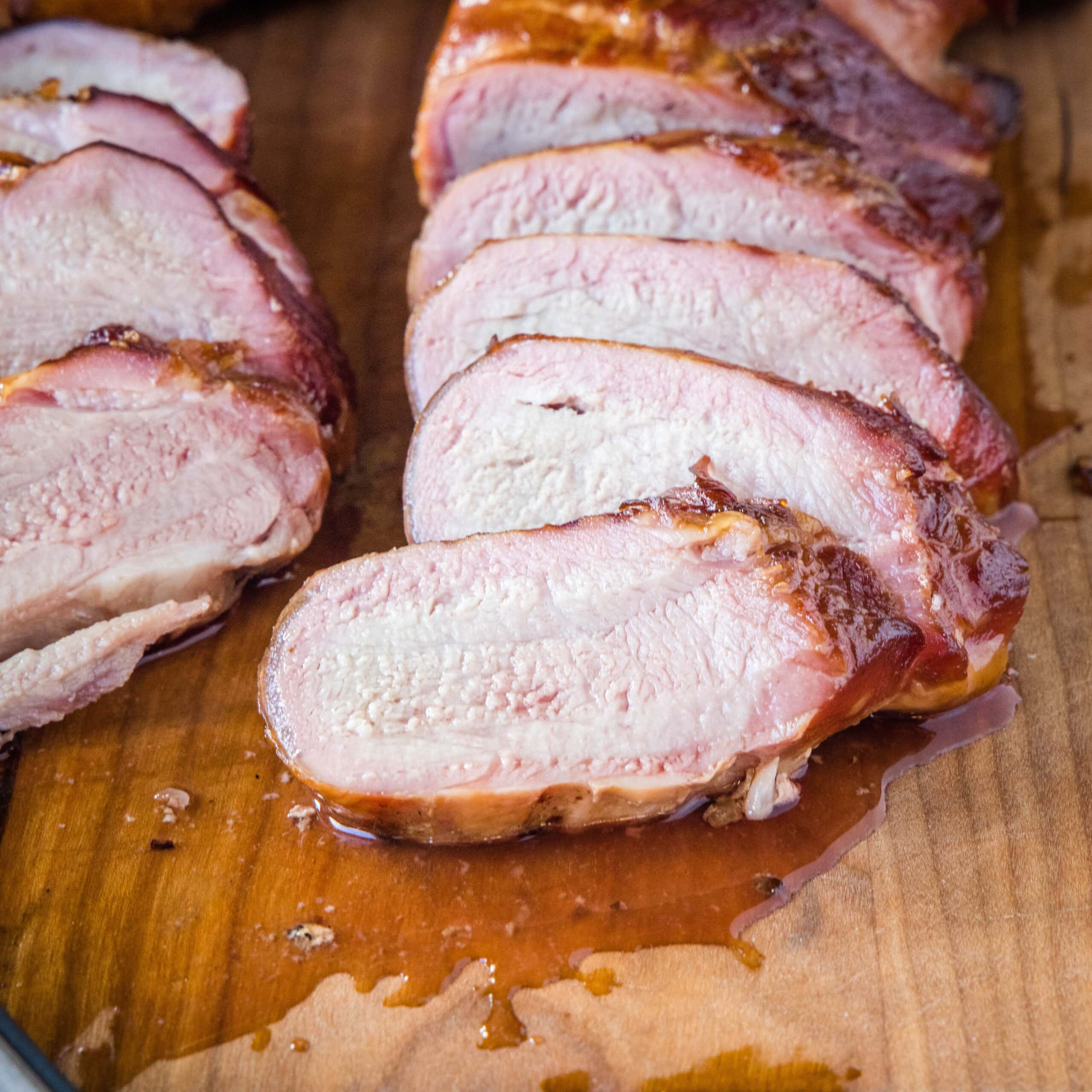 close up smoked pork tenderloin sliced on a cutting board
