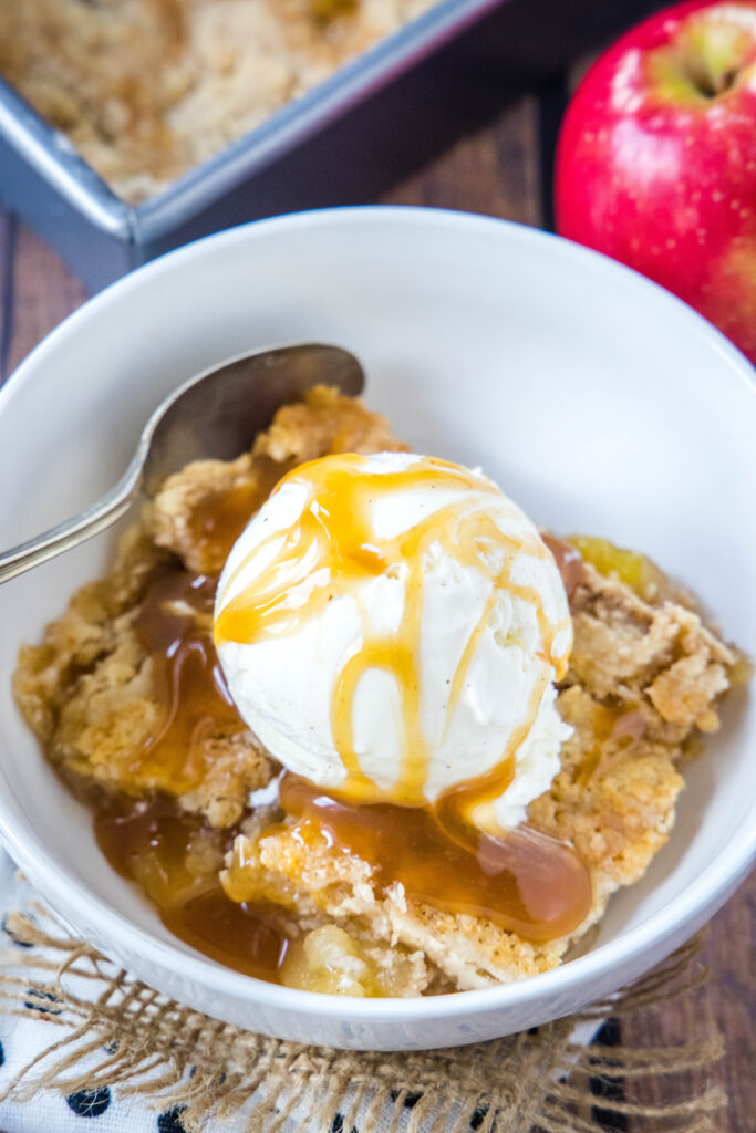 looking down on a bowl of apple dump cake with ice cream and caramel