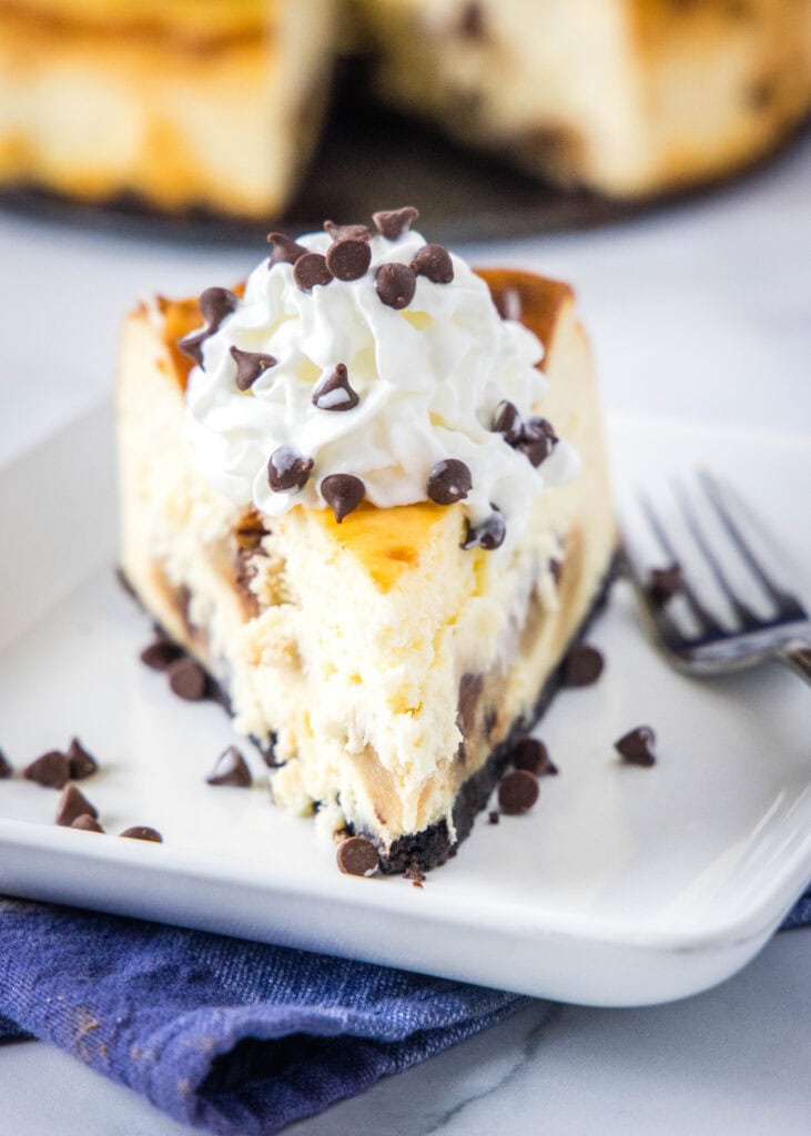 slice of cheesecake with cookie dough pieces on a white plate