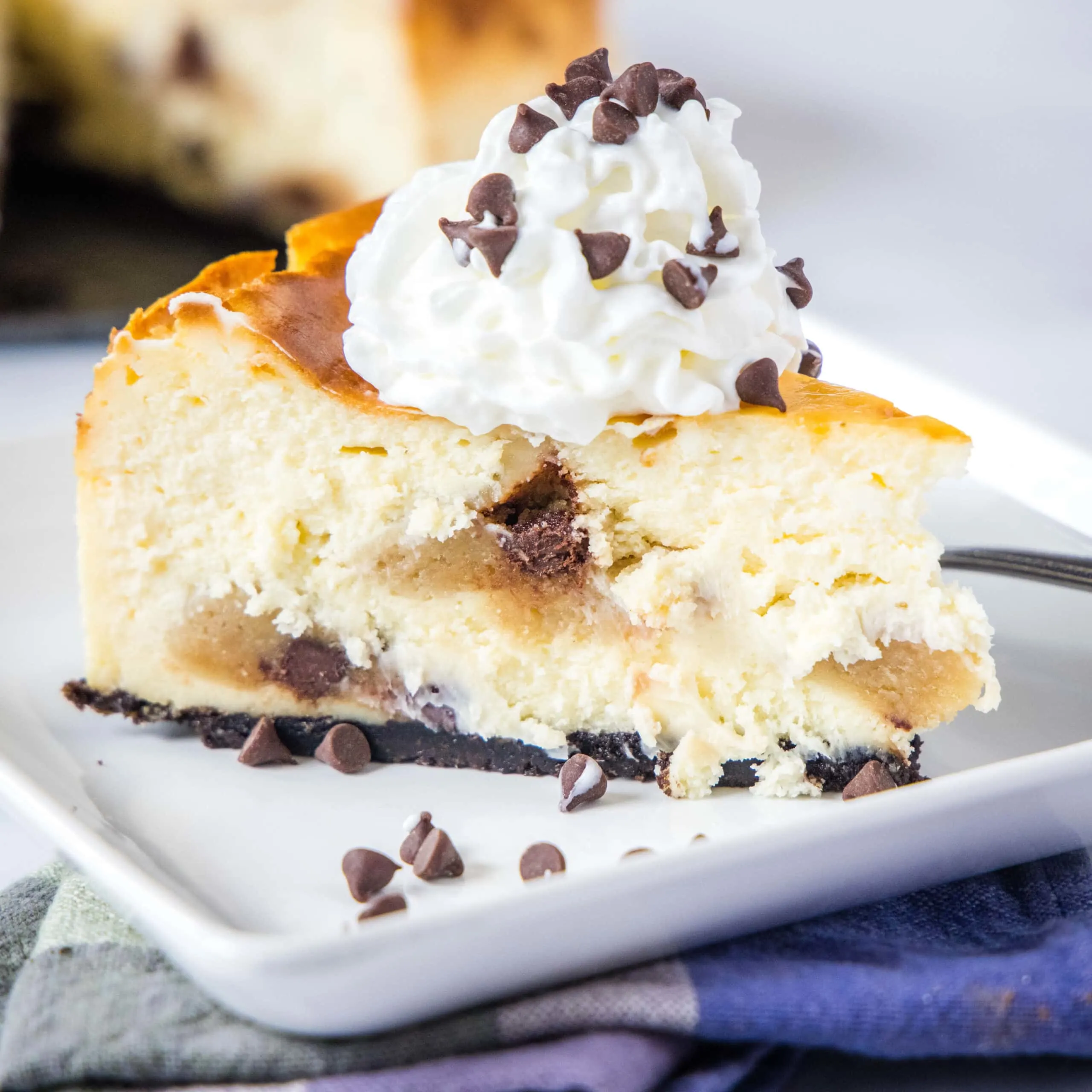close up cookie dough cheesecake on a plate topped with whipped cream