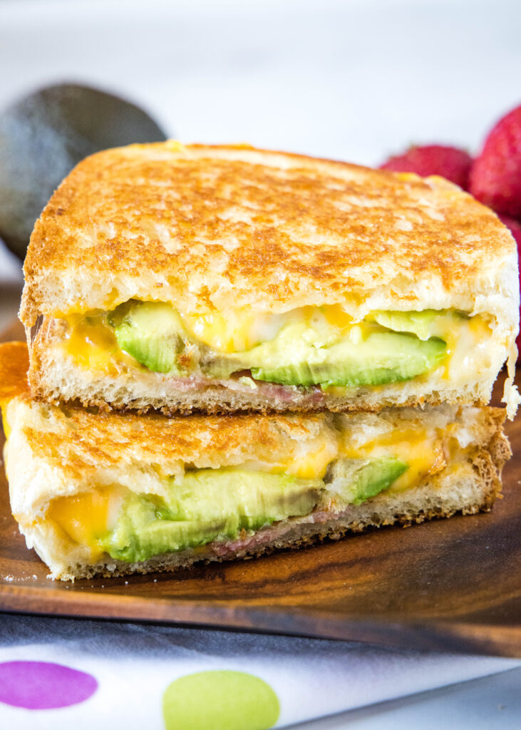 avocado grilled cheese sandwich cut in half and stacked on a plate