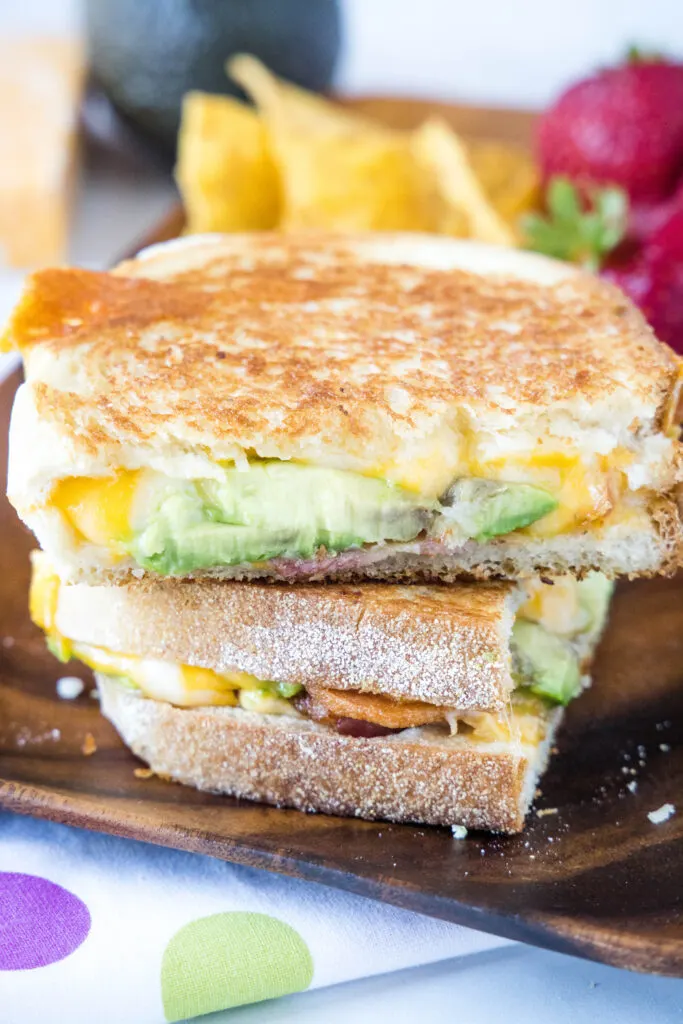 grilled cheese sandwich with avocado cut in half on a plate