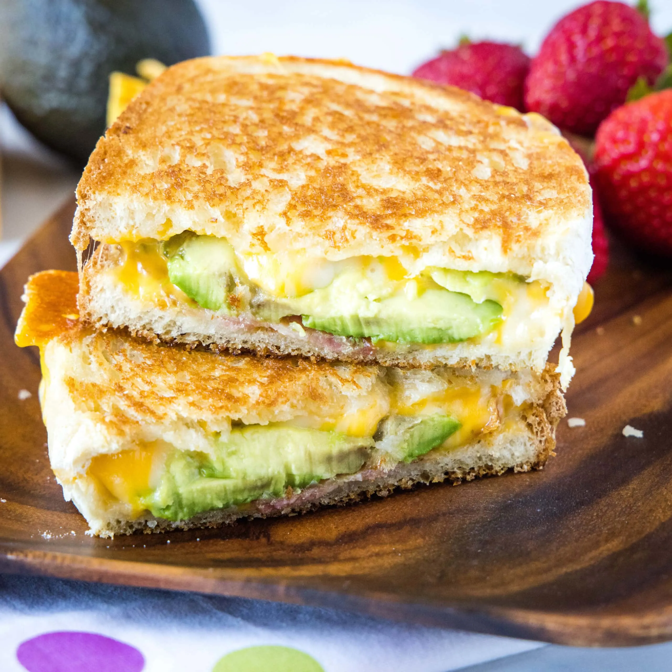 cropped square image of avocado grilled cheese sandwich cut in half