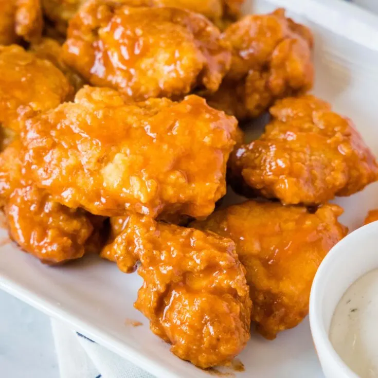 close up boneless chicken wings on a white plate with ranch
