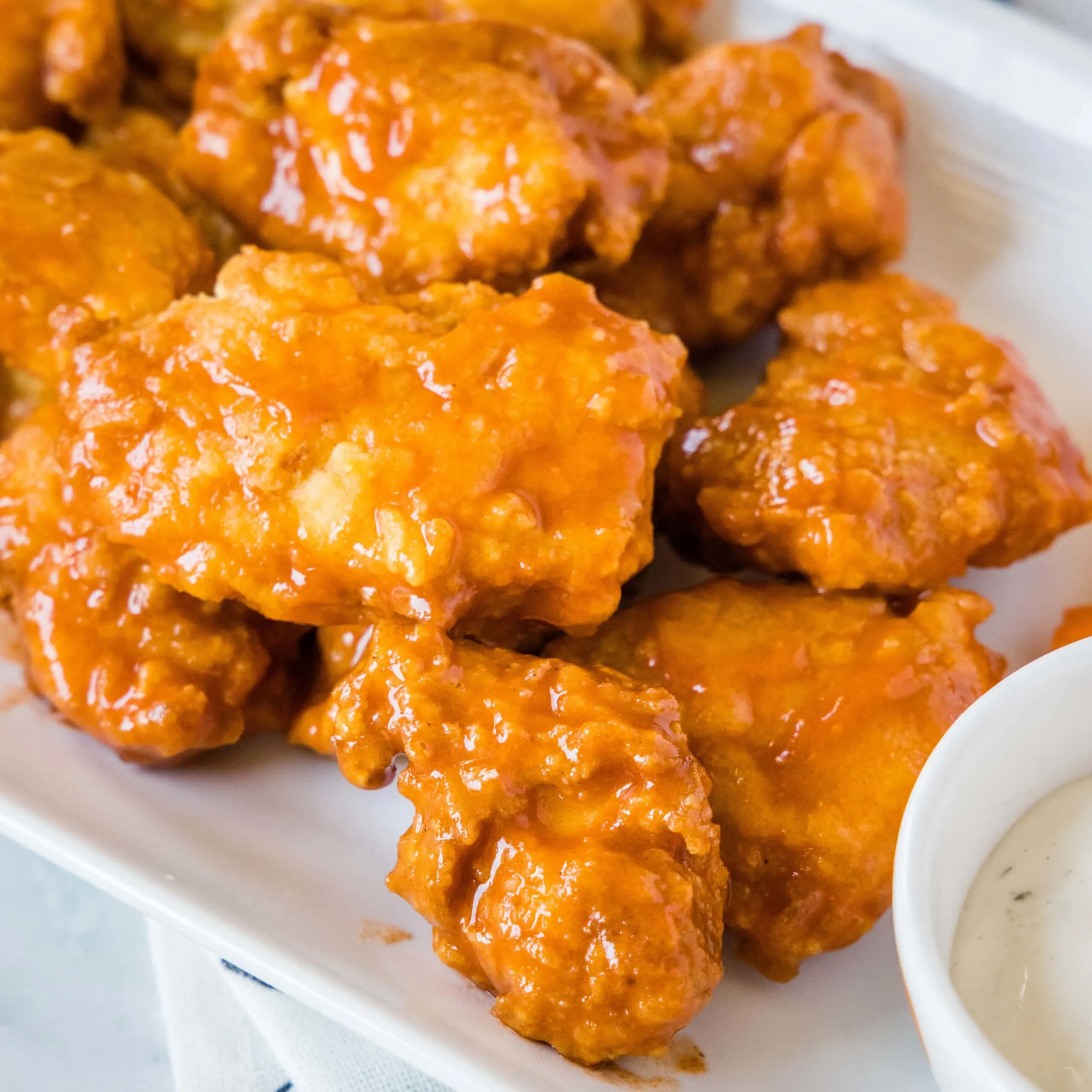 close up boneless chicken wings on a white plate with ranch