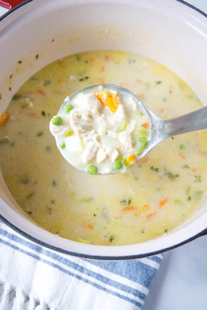 chicken pot pie soup in a pot with a laddle