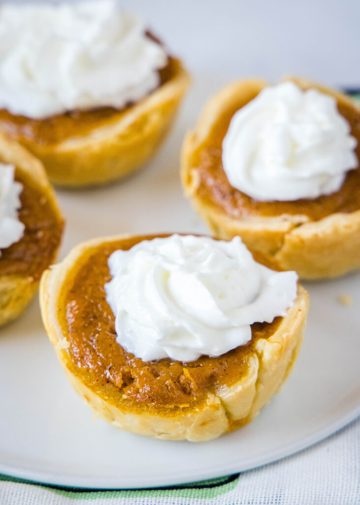 a serving plate with pumpkin pie topped with whipped cream