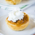 close up individual pumpkin pie on a white plate