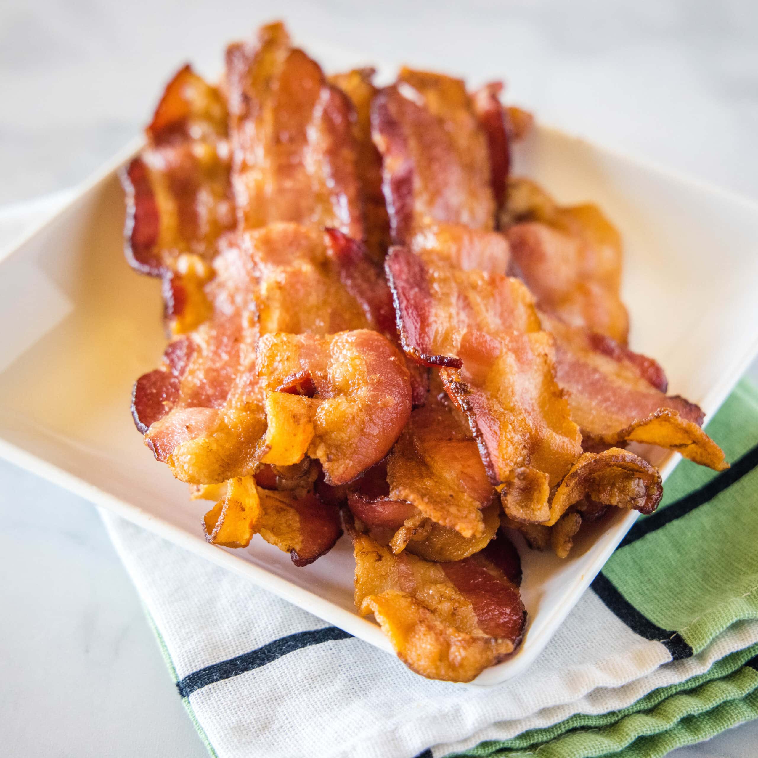 close up strips of bacon on a white plate