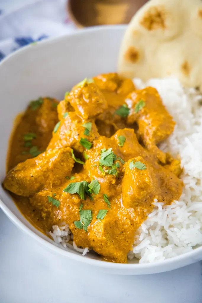 indian butter chicken over rice in a white bowl