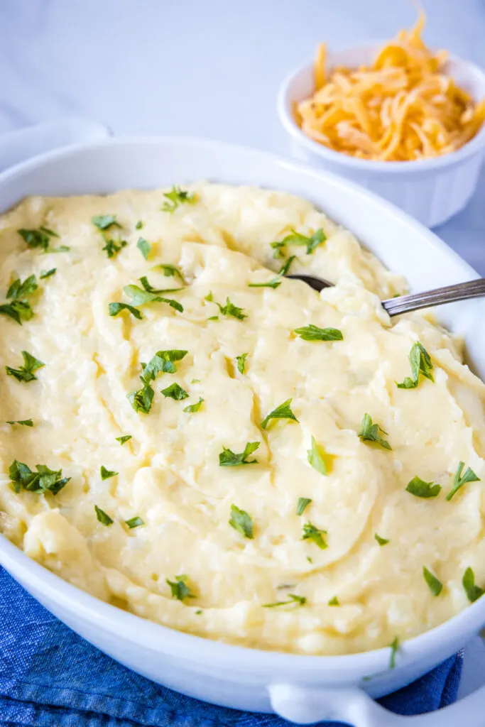 cheesy mashed potatoes in a baking dish topped with parsley