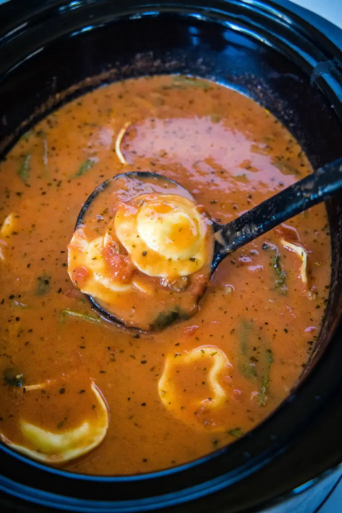 a ladle in the crockpot with tortellini soup