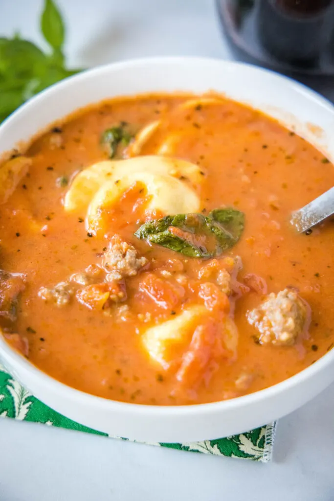 a bowl with a spoon in it of sausage tortellini soup