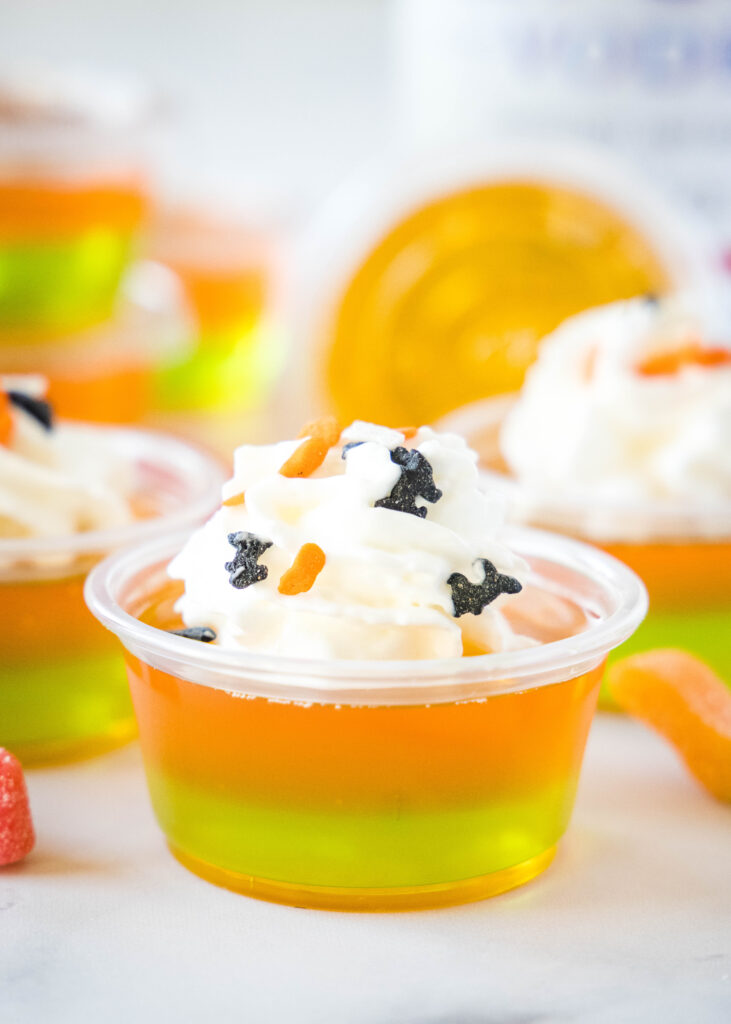 orange and green jello shots with whipped cream