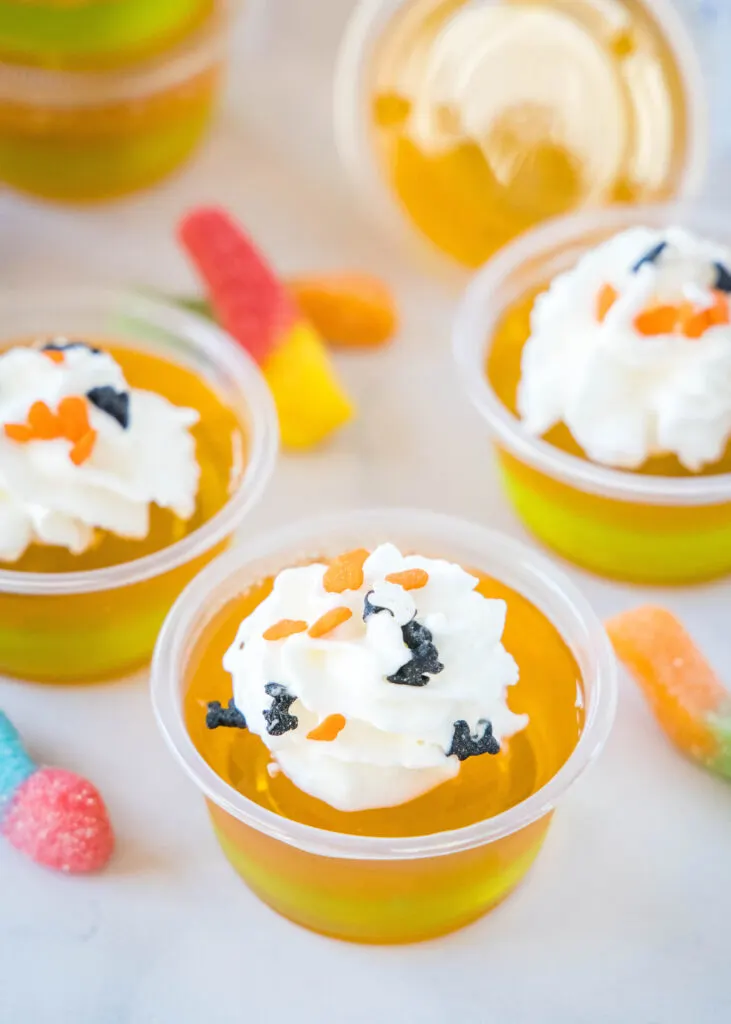 orange and green halloween jello shots topped with whipped cream
