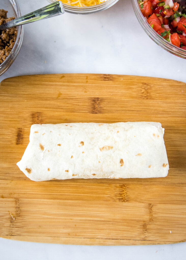 rolled up tortilla like a burrito on a cutting board