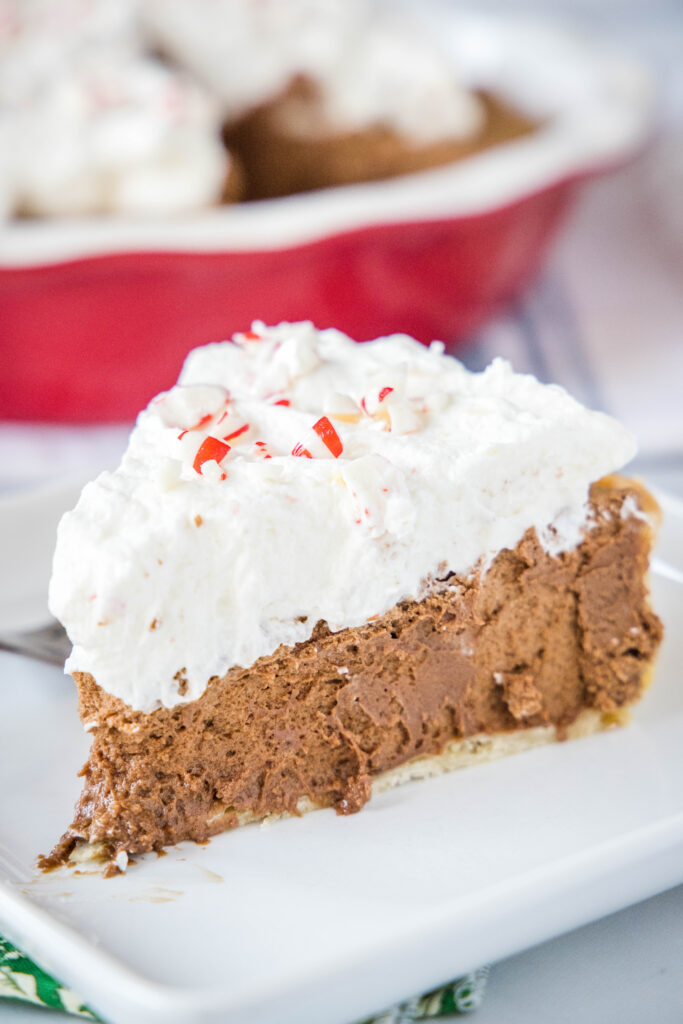 a slice of french silk pie on a white plate topped with candy canes