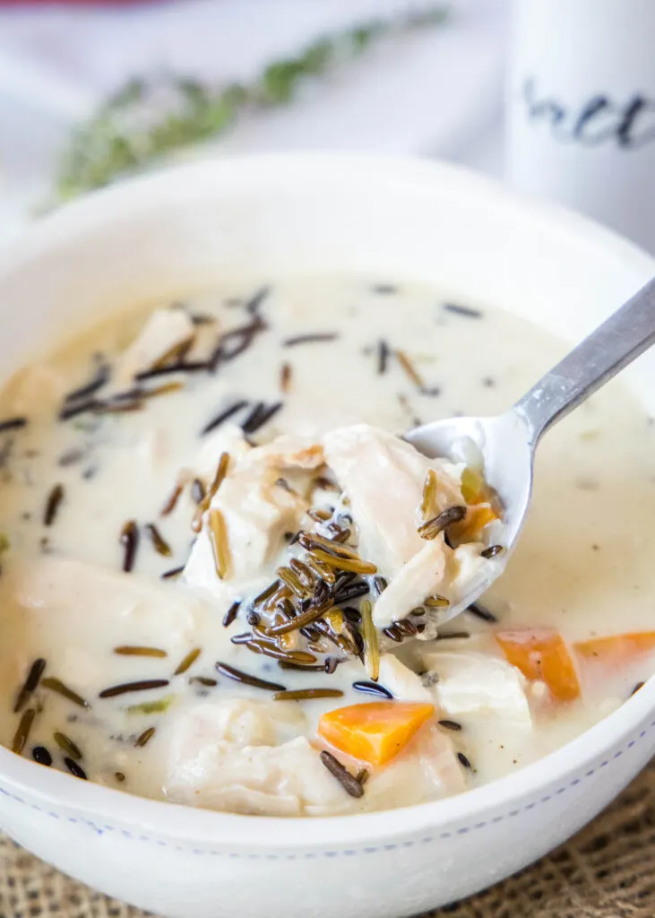 a bowl of wild rice soup with a spoonful being taken out of it