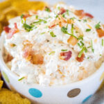 cropped square image of dip in a bowl with bacon on top