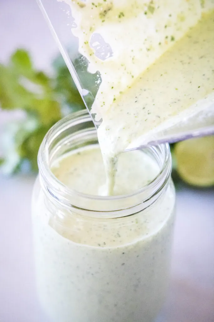 pouring tomatillo ranch dressing from blender into a glass jar