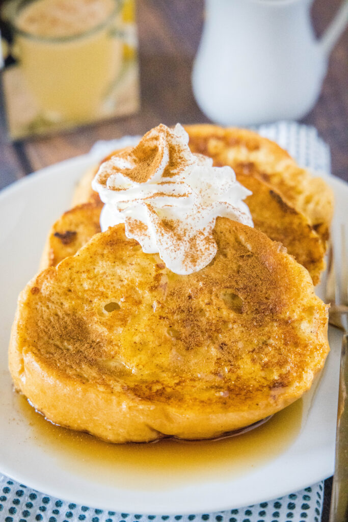 a plate of french toast topped with whipped cream, syrup, and cinnamon