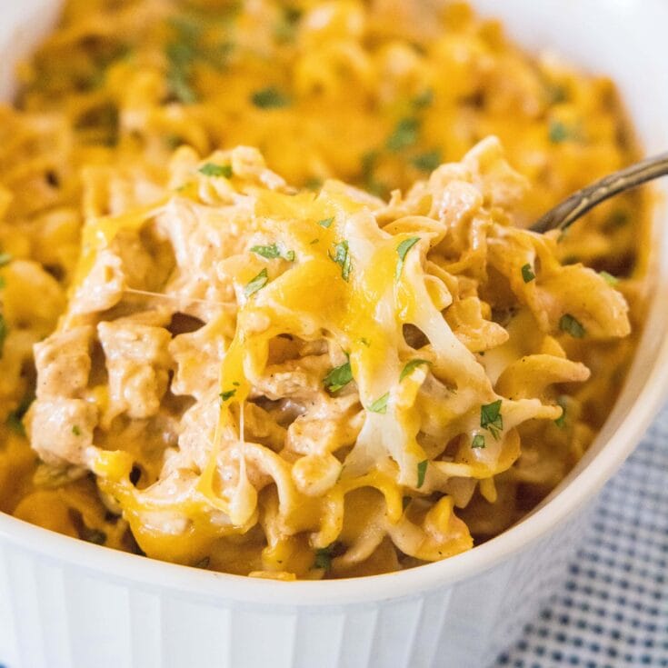 close up scooping chicken pastas out of baking dish