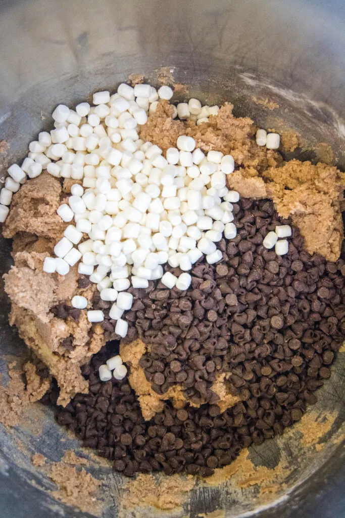 adding chocolate chips and marshmallows to cookie dough