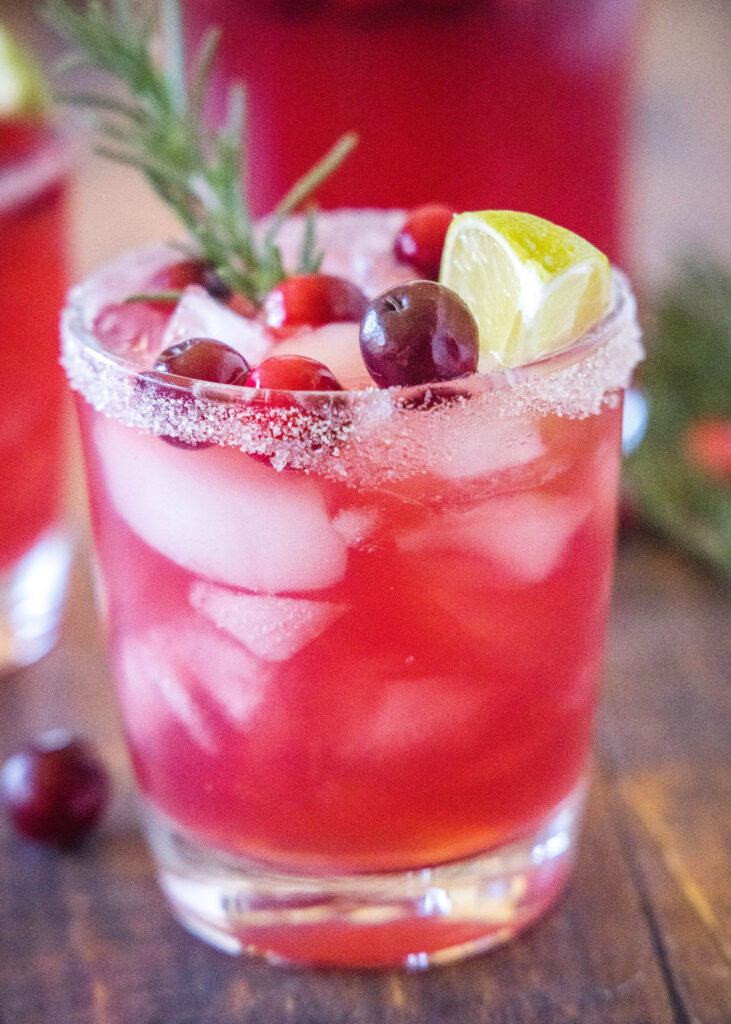 cranberry margarita in a glass with cranberries and rosemary