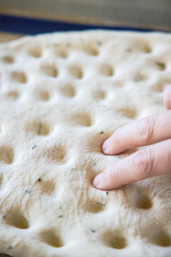 pressing dimples into focaccia bread