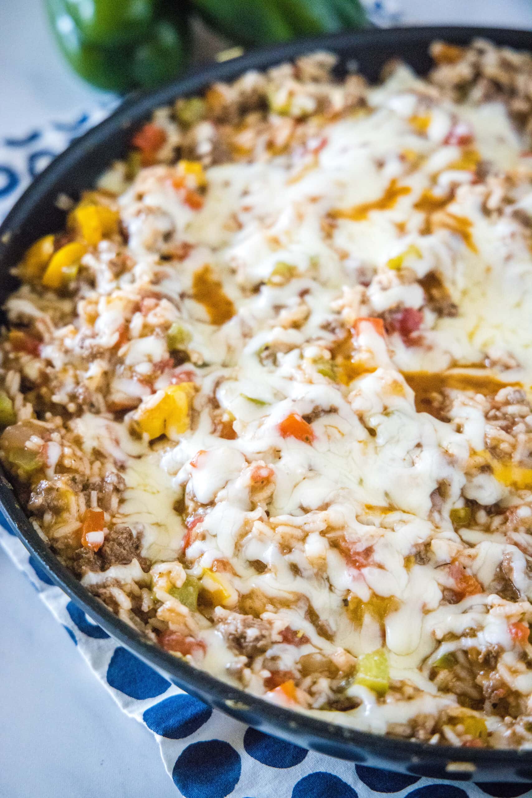 a skillet with melted cheese over ground beef in it