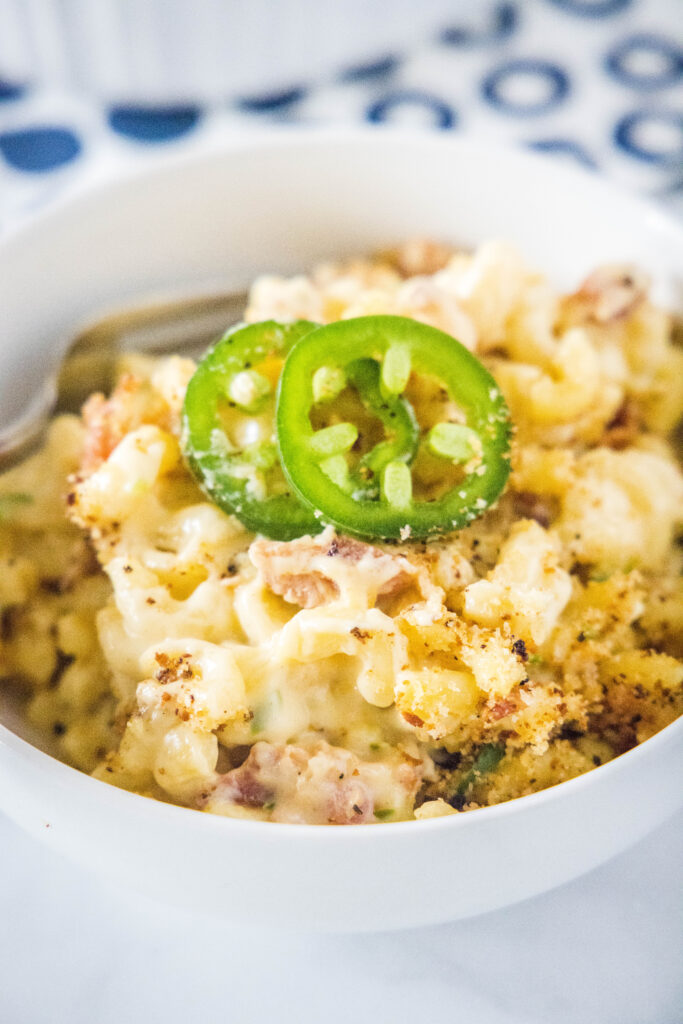 a bowl of macaroni and cheese with jalapenos on top