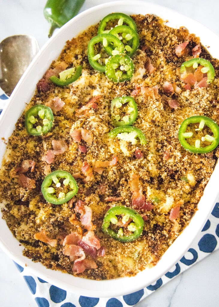 Macaroni and cheese casserole dish topped with jalapenos and bacon